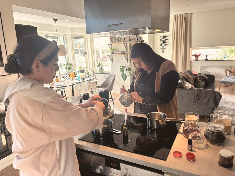 Two women making skincare together at the stove in a home kitchen