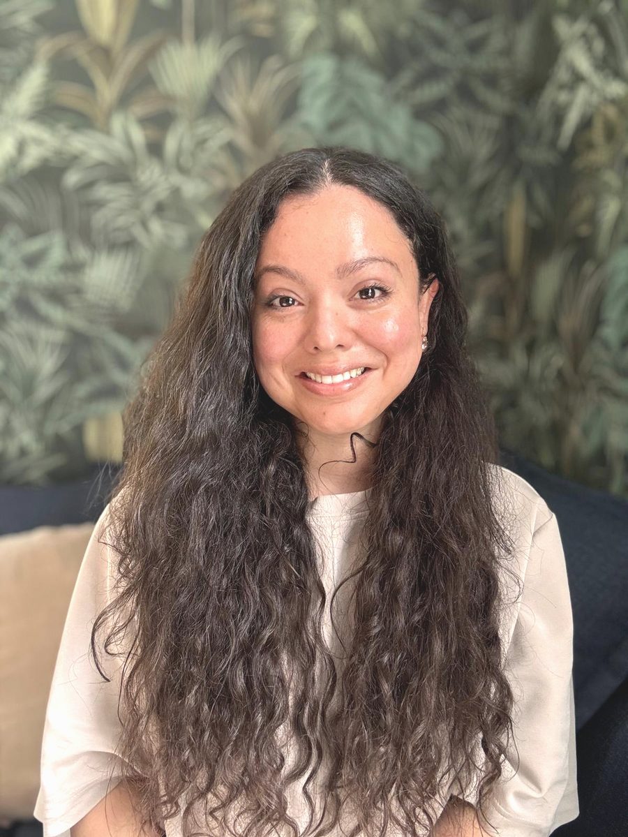The Nosara host smiling in front of a leafy green wall