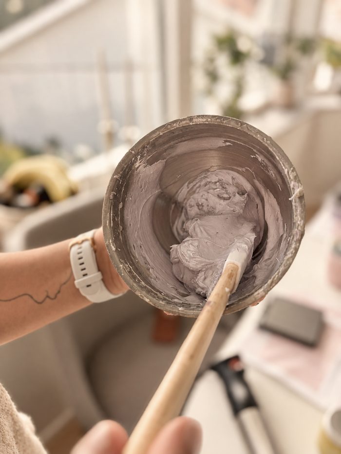 A bowl of soft lilac cream being whipped with a wooden spatula