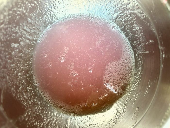 Pink skincare mixture in a steel bowl